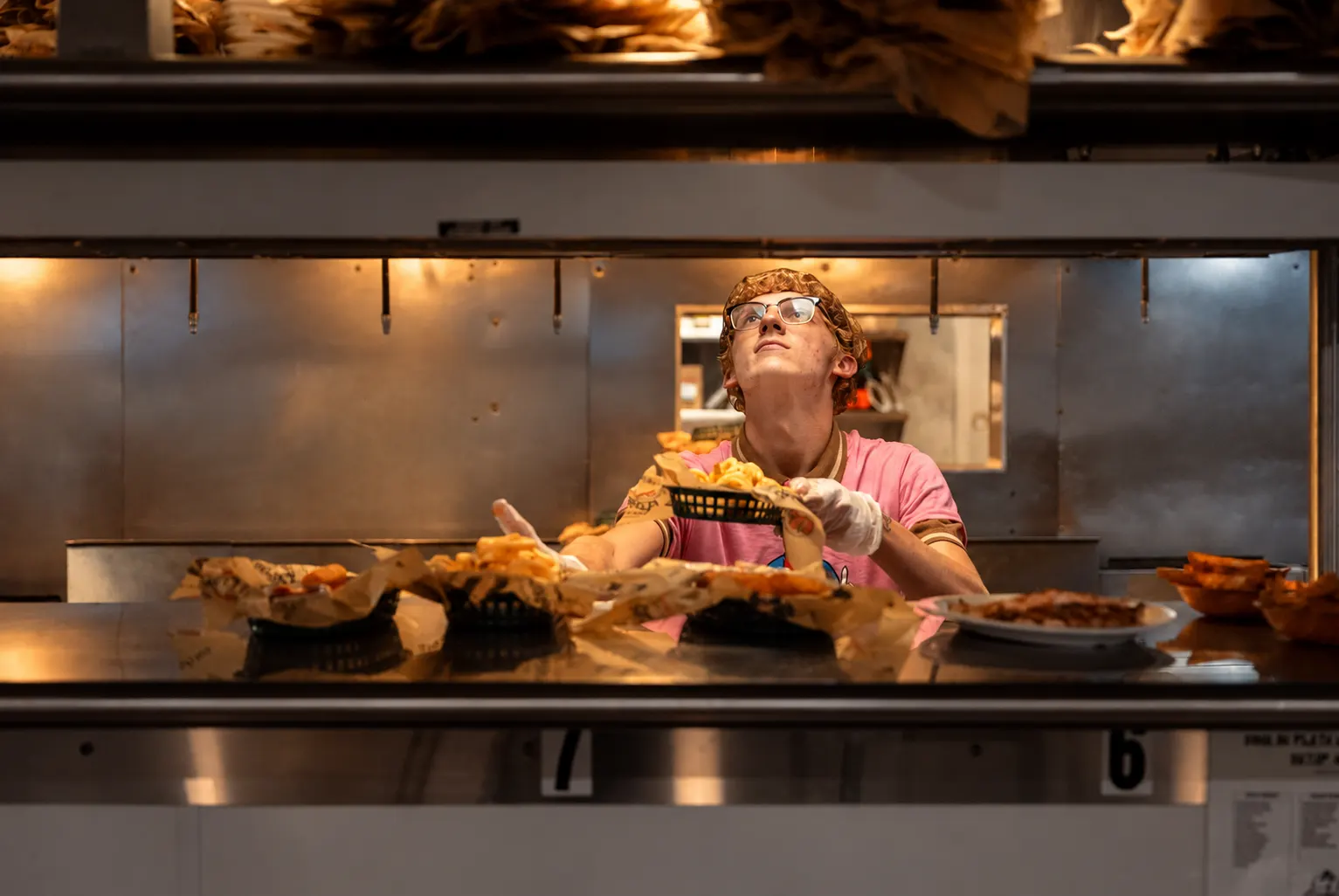 Line cook passing a basket of fries through a restaurant kitchen window