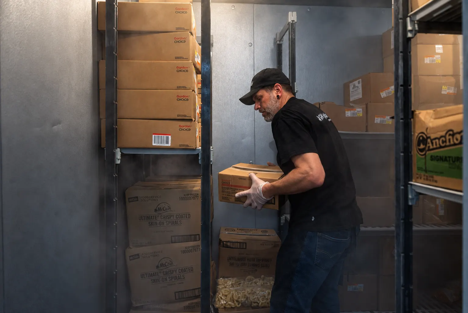 Warehouse worker in gloves carrying a box inside a cold-storage unit